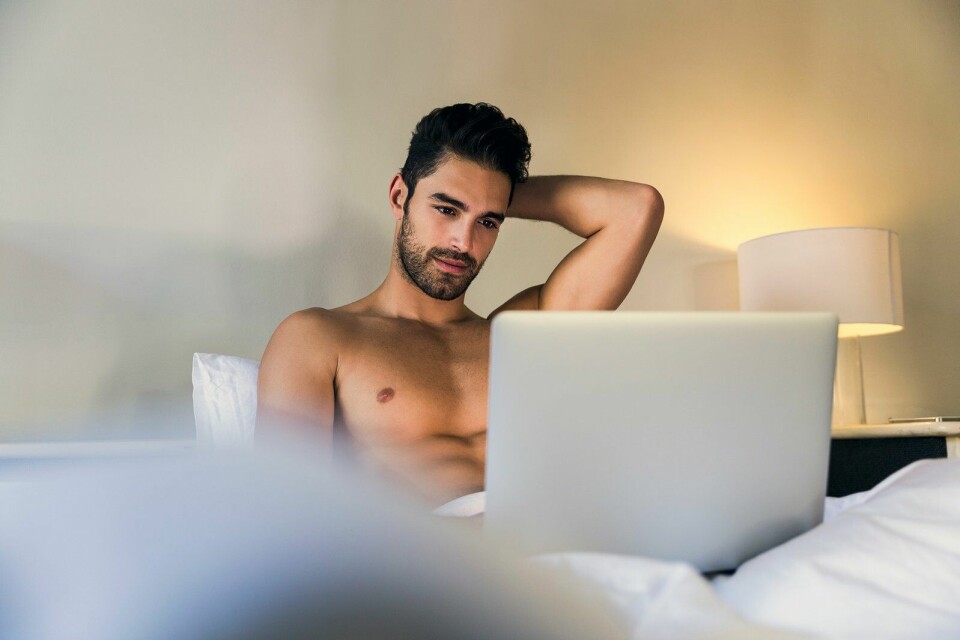 shirtless man in bed met laptop