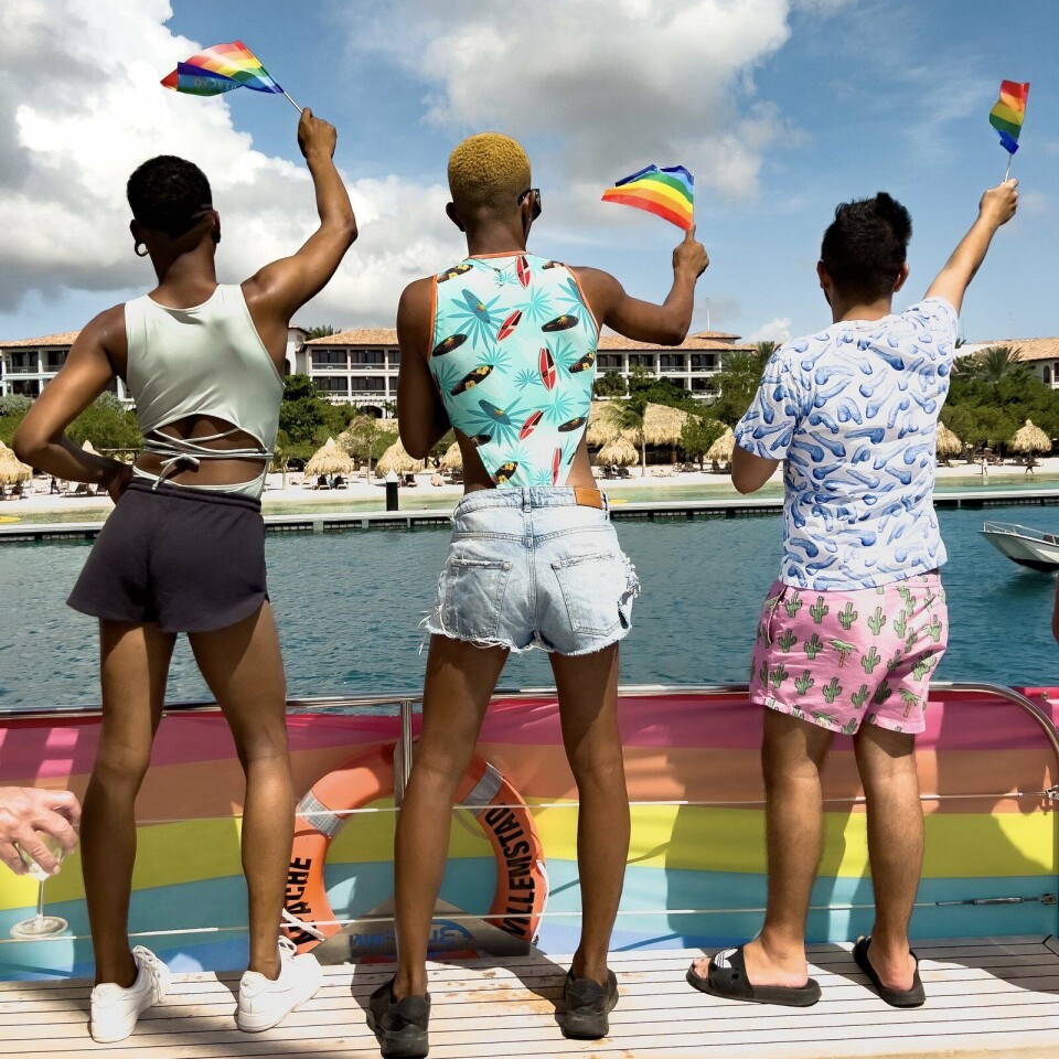 Navigaytion Sea Parade: zorgelozer wordt een zondagmiddag niet. Drie mensen met regenboogvlag op een boot