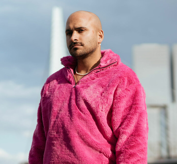 “Het is tijd om te vechten voor een radicaal liefdevolle wereld” Rocher Koendjbiharie in roze trui voor de Erasmusbrug