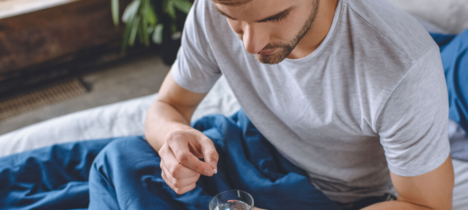 8) doxypep: wondermiddel of gevaar voor de volksgezondheid? high angle view of young man with headache putting pill in glass of water in bed at home