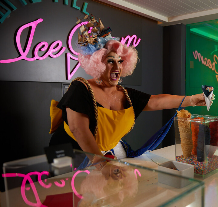 Van drag diva’s tot fine dining: cruisen in luxe met Virgin Voyages Dragqueen serveert een ijsje aan boord van een Virgin Voyage-cruiseschip