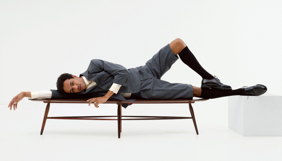 Schoenen, overhemd en pak: via Tommy Page / sokken: Falke Jesse Mensah ligt op een bank