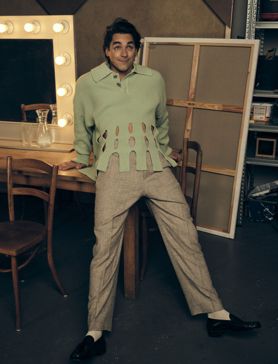 Trui: Nanushka | pantalon: Sandro | sokken: Falke | loafers: Sebago Mark Baanders leunt op een tafel