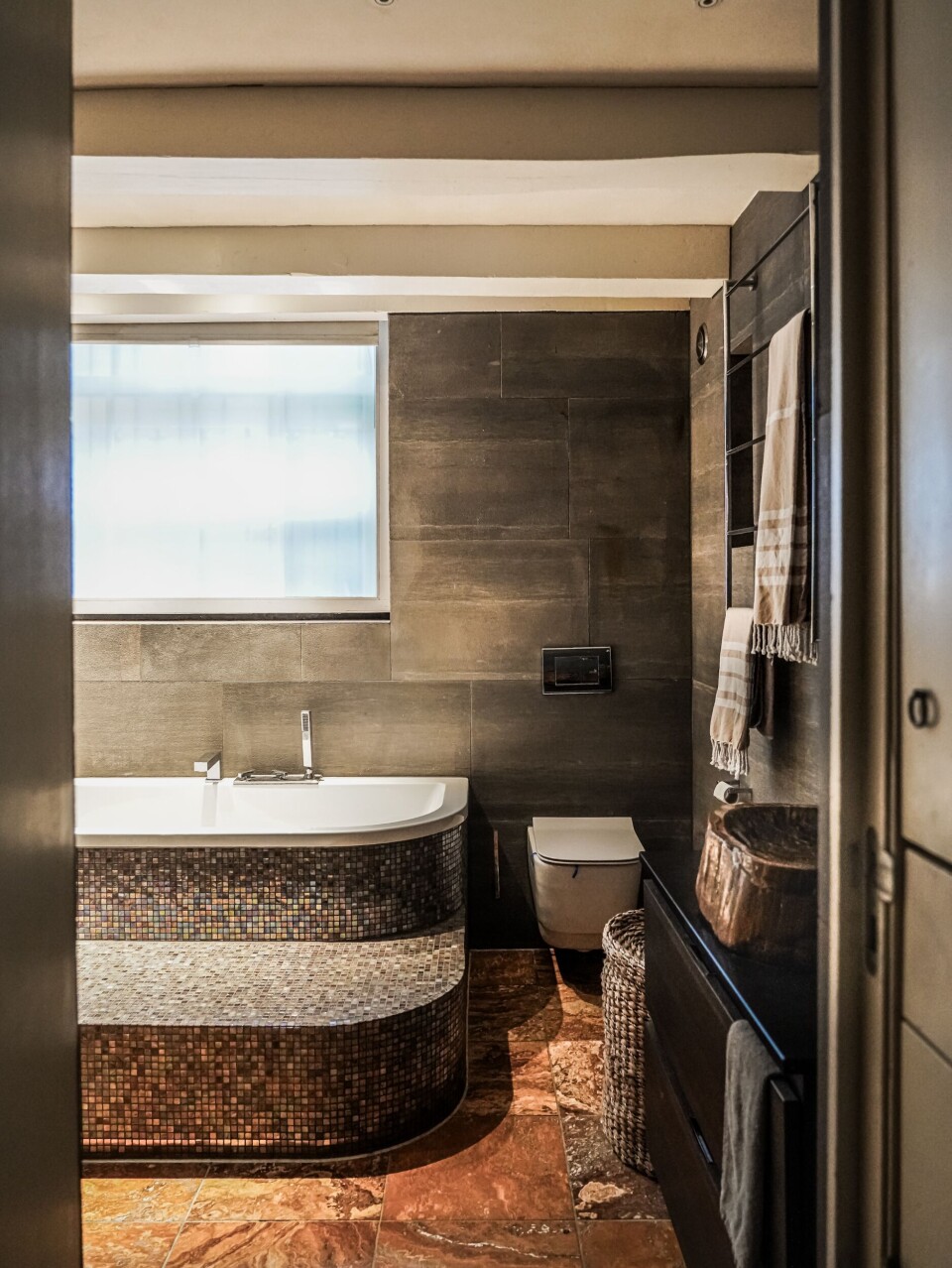 Het spa-achtige bad is bekleed met glasmozaïek (via Bisazza). Het spa-achtige bad is bekleed met glasmozaïek (via Bisazza).