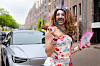Jennifer Hopelezz met ijsje en waaier poseert lachend in een woonstraat.