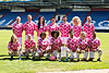Groep voetballers poseert op een grasveld in een stadion in roze wedstrijdkleding.