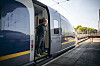 Reiziger in de deuropening van een Eurostar trein aan een zonnig perron.