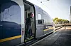 Reiziger in de deuropening van een Eurostar trein aan een zonnig perron.