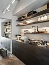 Moderne koffiehoek met espressomachine, open planken en donker houten kasten.