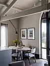 Moderne eetkamer met ronde tafel, stoelen, kunst aan de muur en een hoge glazen deur.