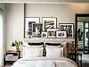 Lichte slaapkamer met wit bed, planten, kunst aan de muur en een donkere kast.